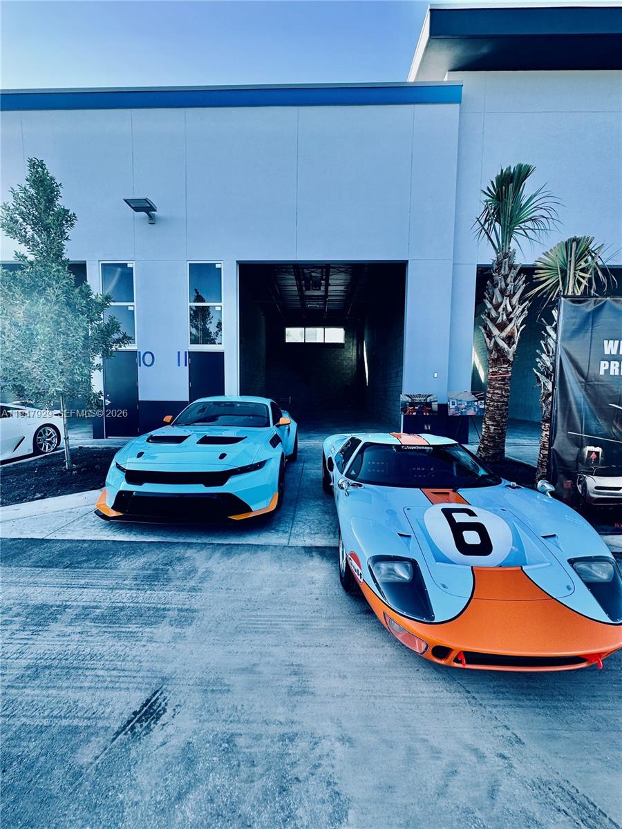 Two sports cars with Gulf livery are parked in front of a commercial building — 15375 Corporate Rd # 17, Jupiter FL 33478, JUPITER, FL