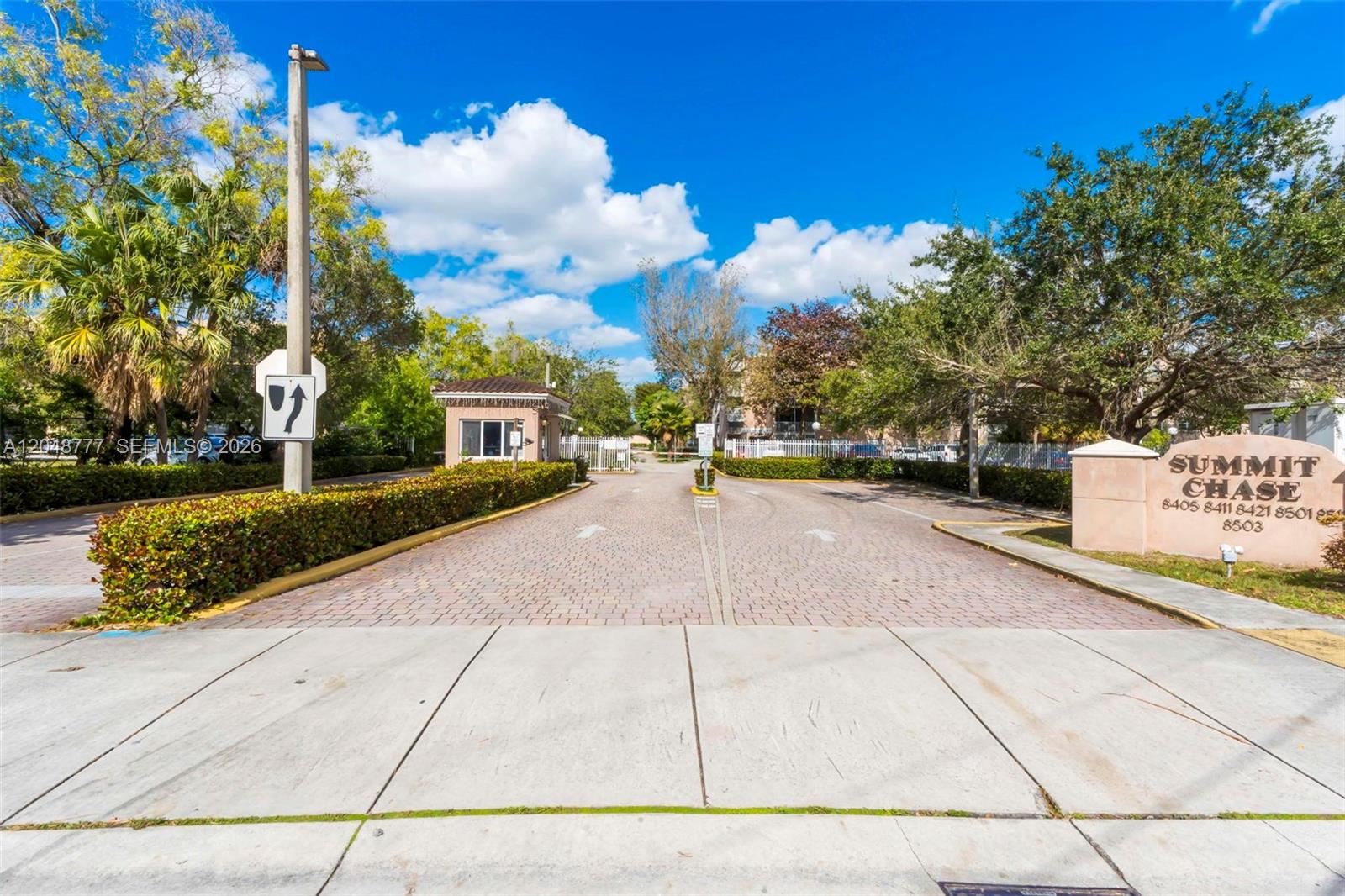 The entrance to a gated community features a brick driveway, a guardhouse, and signage — 8501 NW 8th St # 110, Miami FL 33126, MIAMI, FL