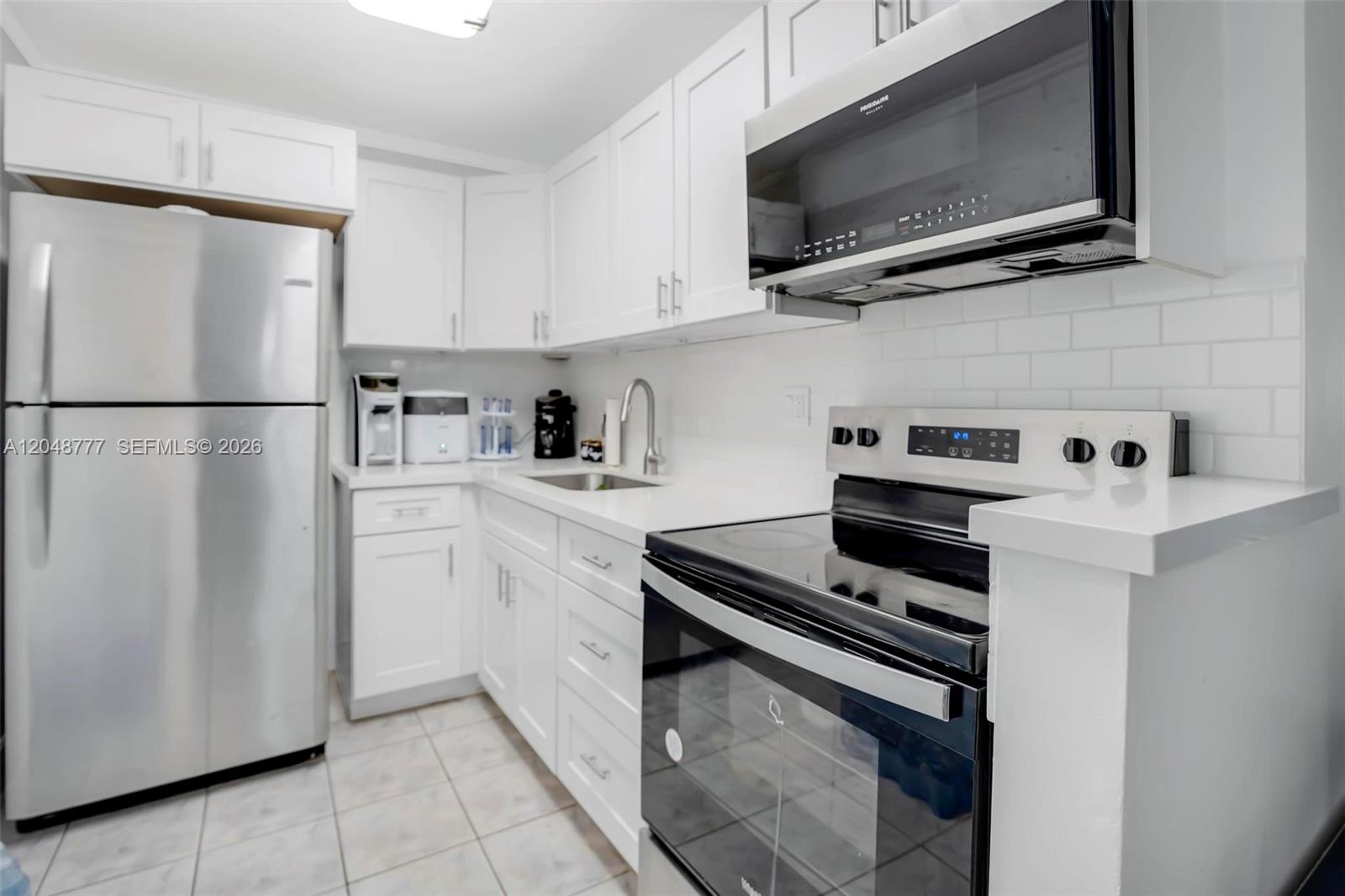 A kitchen features white cabinets, stainless steel appliances, white countertops, and a subway tile backsplash — 8501 NW 8th St # 110, Miami FL 33126, MIAMI, FL