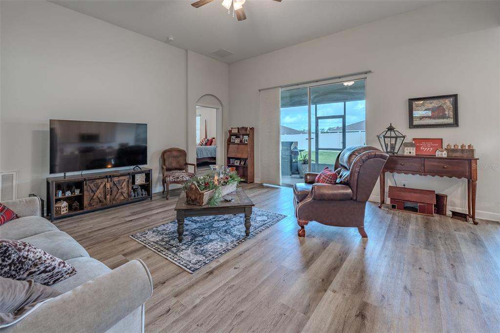 A living room features wood-look flooring, a television console, a leather recliner, and sliding glass doors — 9224 SW 60 COURT ROAD, OCALA, FL
