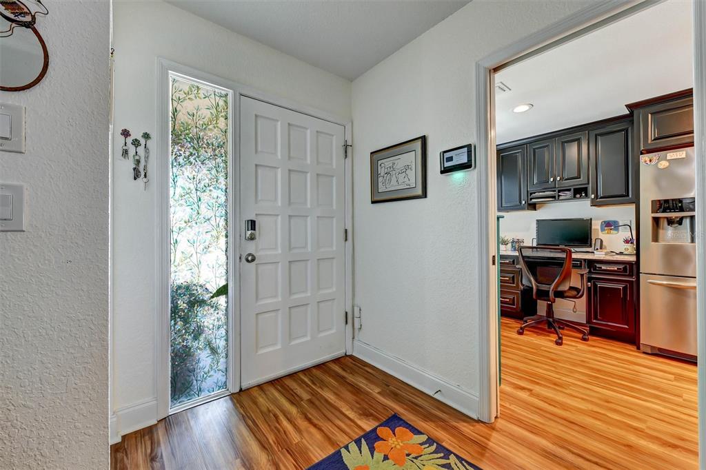 An entryway with a white door, sidelight window, and wood-look flooring leads into a home office — 8352 MEADOWBROOK DRIVE UNIT 10, SEMINOLE, FL