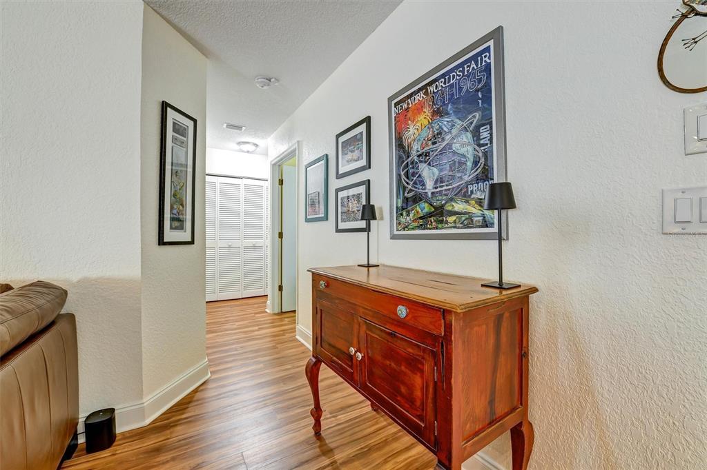 A hallway features wood-look flooring, a wooden console table, and framed wall art — 8352 MEADOWBROOK DRIVE UNIT 10, SEMINOLE, FL