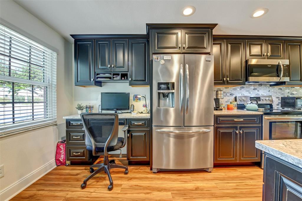A kitchen features dark wood cabinets, stainless steel appliances, and a built-in desk area — 8352 MEADOWBROOK DRIVE UNIT 10, SEMINOLE, FL