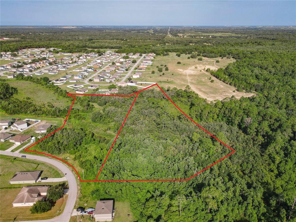 An aerial view shows a wooded, undeveloped lot outlined in red near a residential neighborhood — 0 HUDSON VALLEY DRIVE, KISSIMMEE, FL