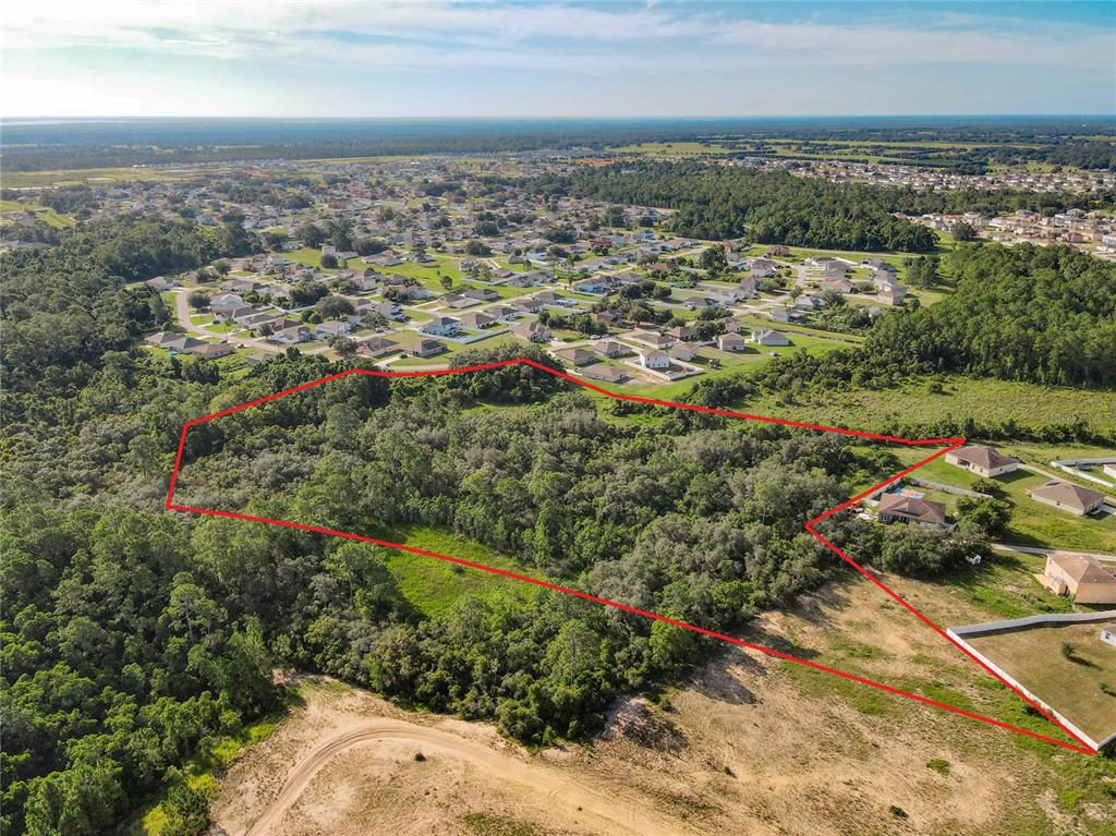 An aerial view shows a wooded plot of land outlined in red near a residential neighborhood — 0 HUDSON VALLEY DRIVE, KISSIMMEE, FL
