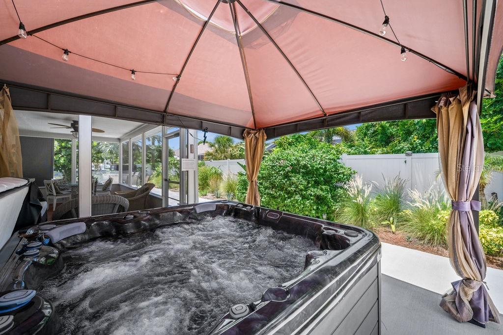 A hot tub sits under a gazebo on a patio next to a screened-in porch — 1024 HORIZON ROAD, VENICE, FL