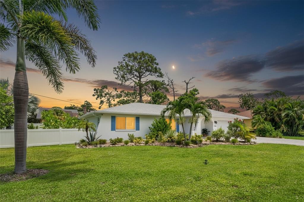 A single-story house with a white exterior, blue shutters, and palm trees at sunset — 1024 HORIZON ROAD, VENICE, FL