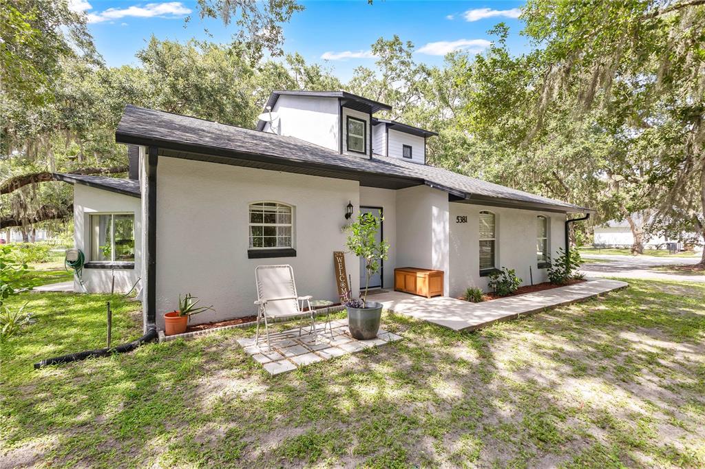 A single-story house with a light gray stucco exterior, dark trim, and a small patio — 5381 ALLIGATOR LAKE ROAD, ST CLOUD, FL