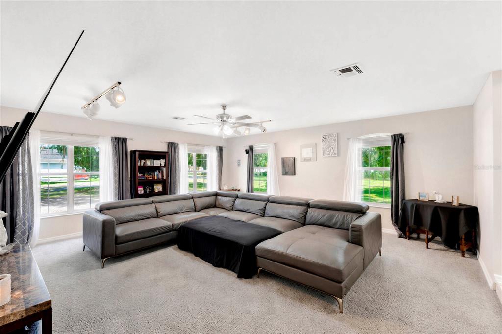 A living room features a large gray sectional sofa, carpeted floors, and multiple windows — 5381 ALLIGATOR LAKE ROAD, ST CLOUD, FL