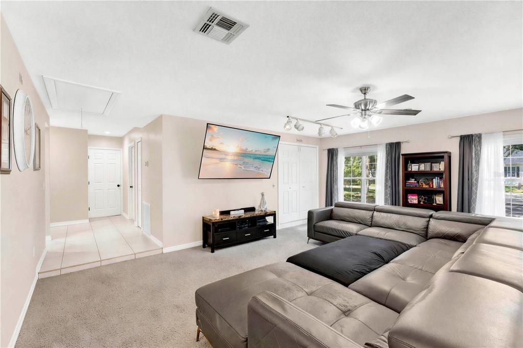 A living room features a grey sectional sofa, a wall-mounted television, and carpeted flooring — 5381 ALLIGATOR LAKE ROAD, ST CLOUD, FL