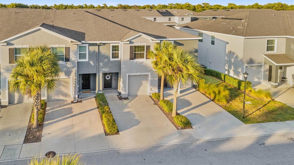 An exterior view of a multi-unit townhouse complex with driveways and palm trees — 8965 INDIGO TRAIL LOOP, RIVERVIEW, FL
