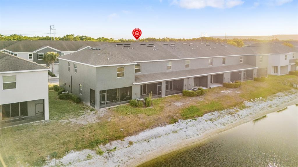 An aerial view shows the rear exterior of a multi-unit townhouse building beside a pond — 8965 INDIGO TRAIL LOOP, RIVERVIEW, FL