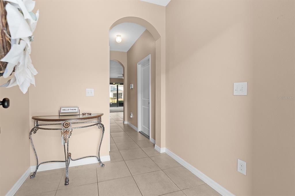 An entryway with beige walls, tile flooring, an arched doorway, and a decorative console table — 8965 INDIGO TRAIL LOOP, RIVERVIEW, FL