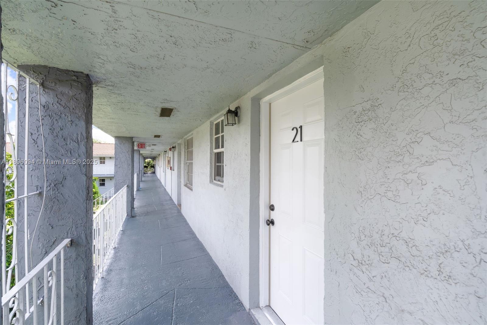 An outdoor apartment walkway features a white door labeled 21 and a metal railing — 4050 NW 135th St # 11, Opa-Locka FL 33054, OPA-LOCKA, FL