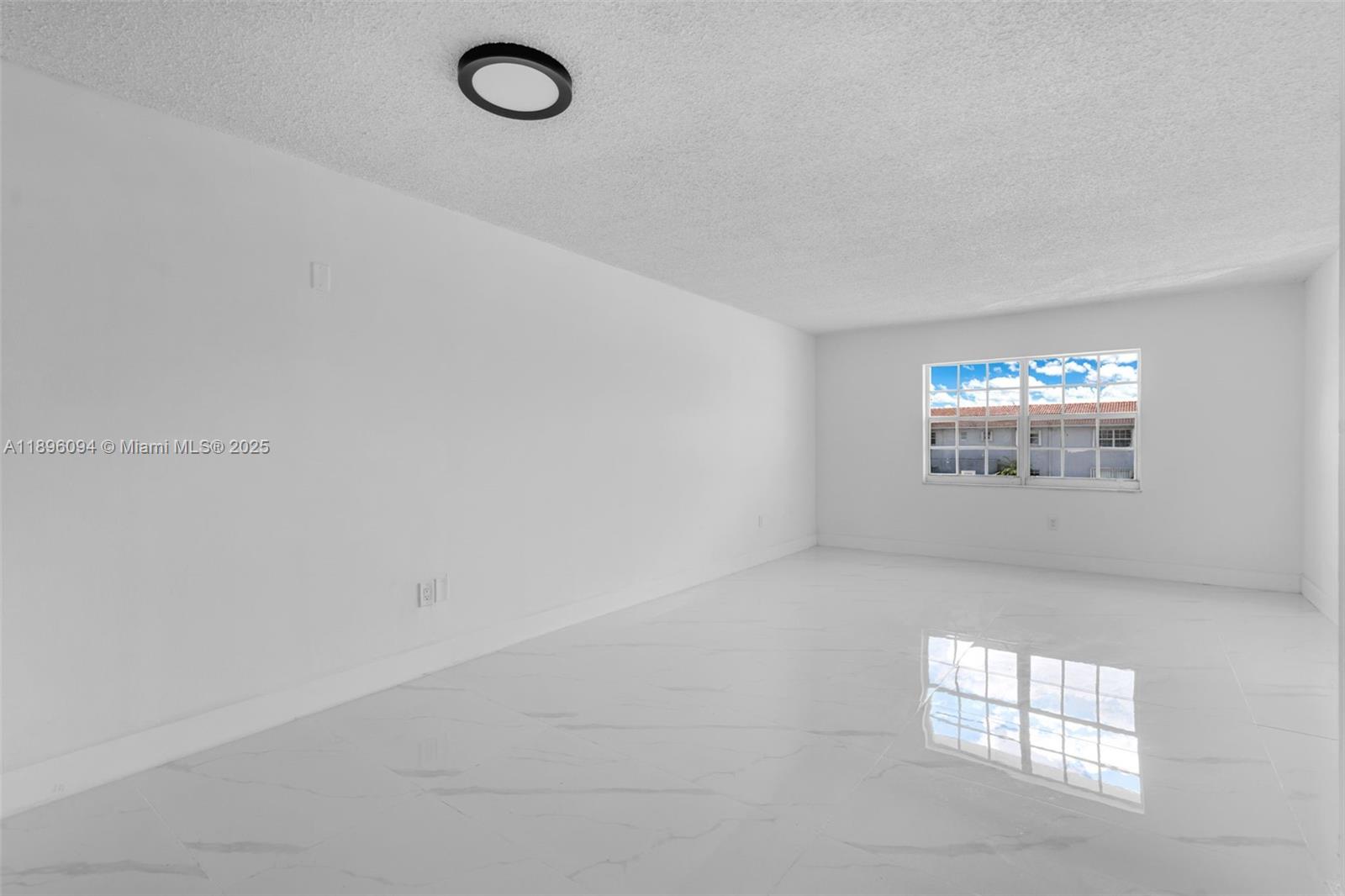 An empty room features white walls, glossy white tile flooring, and a single window — 4050 NW 135th St # 11, Opa-Locka FL 33054, OPA-LOCKA, FL