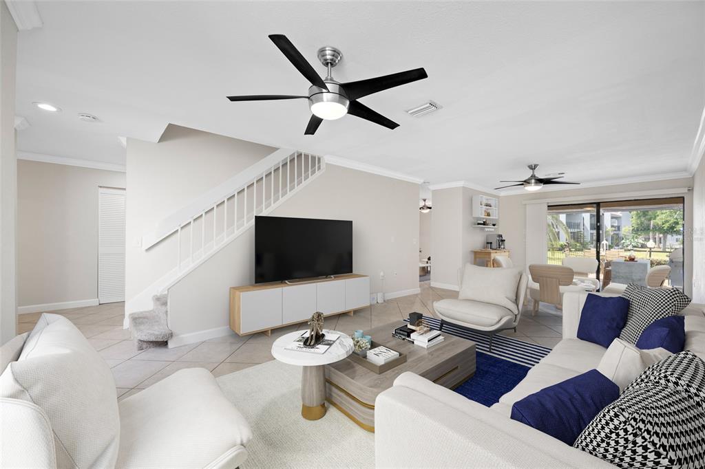 A living room features a ceiling fan, a television on a console, and tiled flooring — 10416 SAINT TROPEZ PLACE, TAMPA, FL