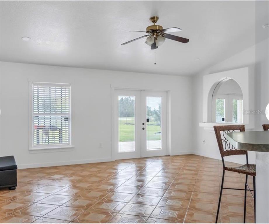 A room with white walls, tile flooring, a ceiling fan, and French doors leading outside — 34 BRADFORD, KISSIMMEE, FL