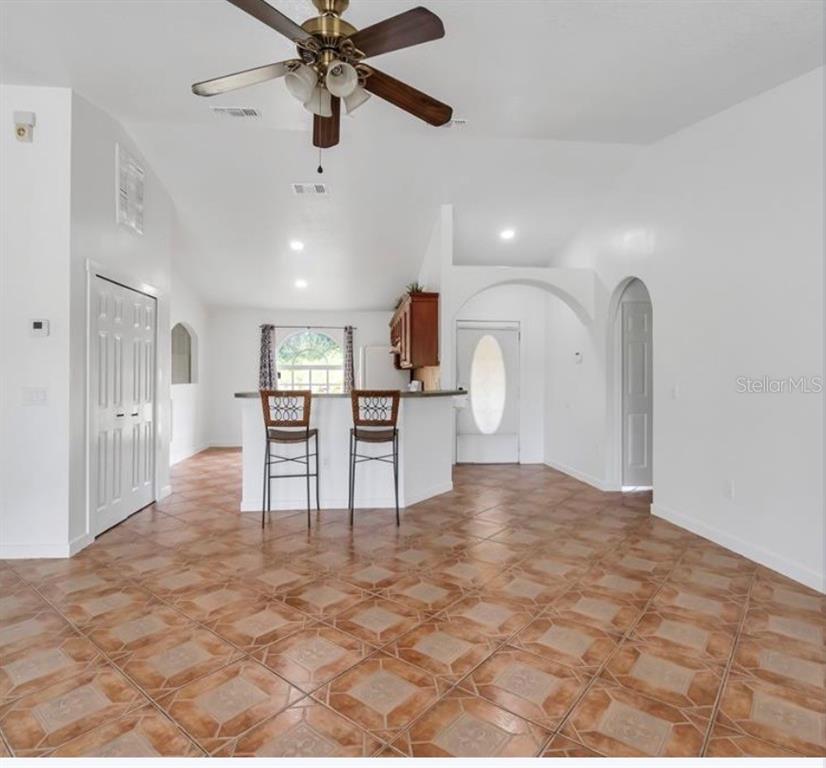 A bright room with tiled floors, a ceiling fan, and a kitchen breakfast bar — 34 BRADFORD, KISSIMMEE, FL