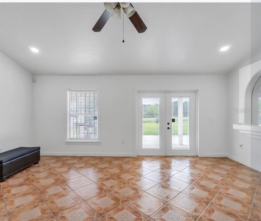 A room with white walls, tile flooring, a ceiling fan, a window, and French doors — 34 BRADFORD, KISSIMMEE, FL