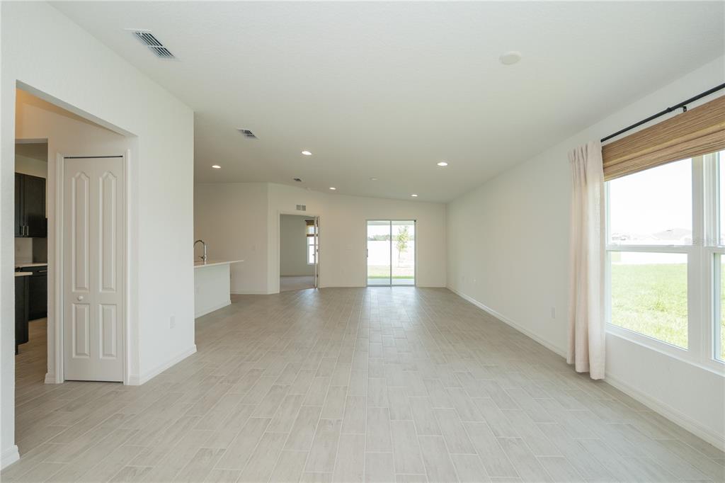 An open-concept living area features light-colored tile flooring, recessed lighting, and a sliding glass door — 3512 ELLIOTT PLACE, BARTOW, FL