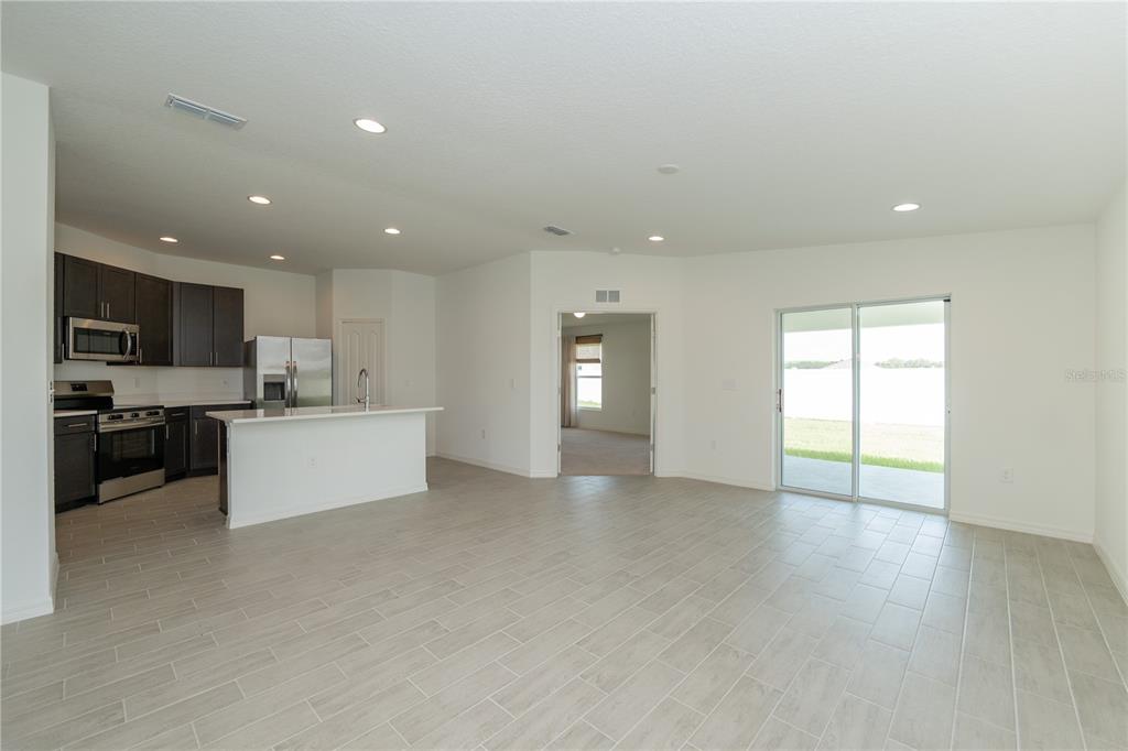 An open-concept kitchen and living area featuring dark cabinets, a white island, and tile flooring — 3512 ELLIOTT PLACE, BARTOW, FL