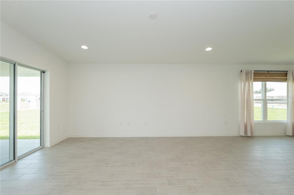 A bright, empty living room features white walls, recessed lighting, tile flooring, and sliding glass doors — 3512 ELLIOTT PLACE, BARTOW, FL