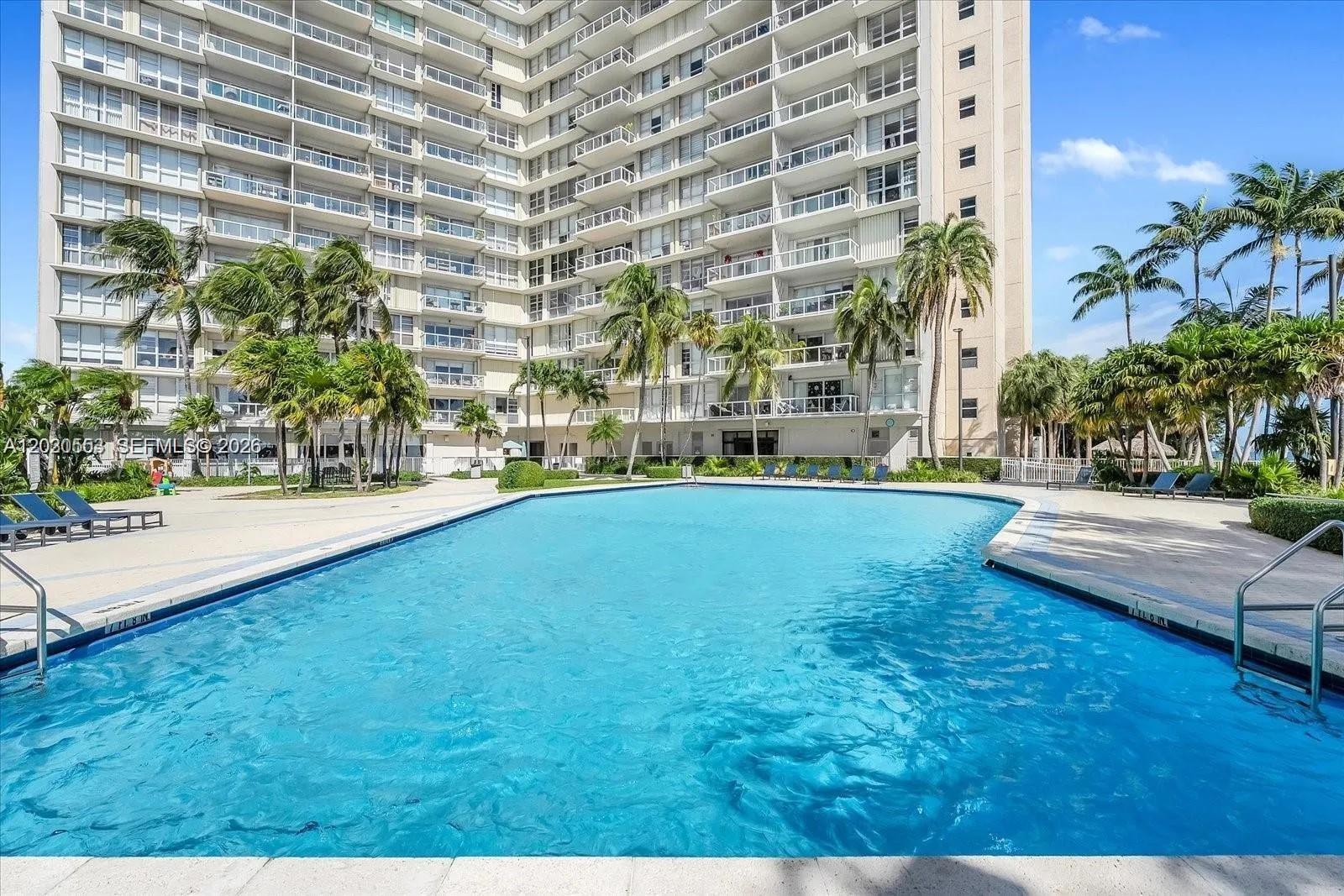 A large rectangular swimming pool sits in front of a multi-story residential apartment building — 2451 Brickell Ave # 5G, Miami FL 33129, MIAMI, FL