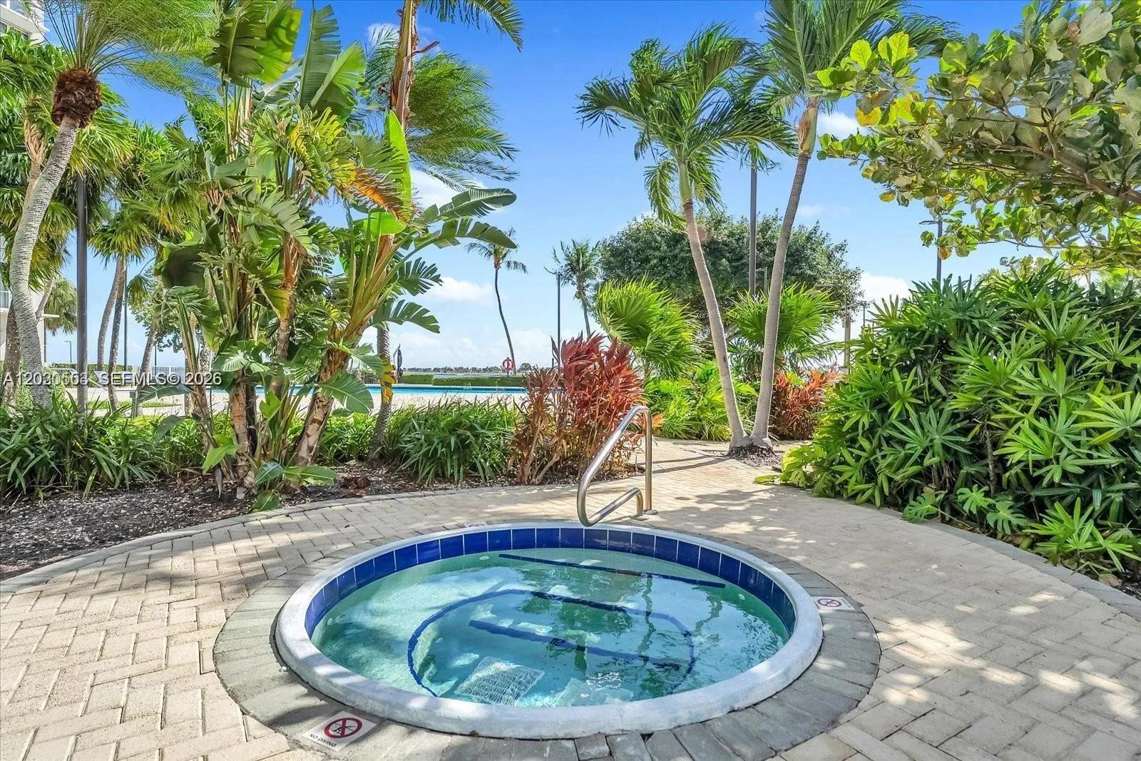 A circular hot tub sits on a paved patio surrounded by lush tropical landscaping — 2451 Brickell Ave # 5G, Miami FL 33129, MIAMI, FL