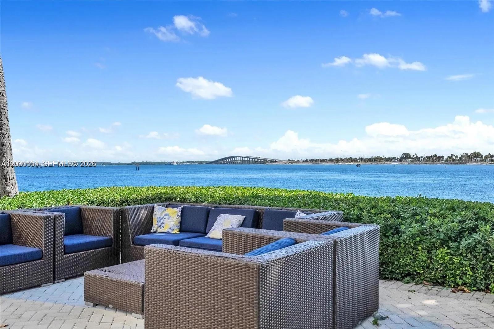An outdoor patio features wicker furniture overlooking a bay with a bridge in the distance — 2451 Brickell Ave # 5G, Miami FL 33129, MIAMI, FL