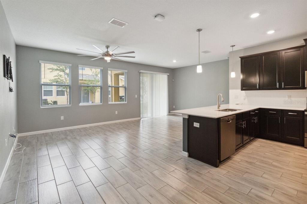 An open-concept kitchen and living area features dark wood cabinets, white countertops, and tile flooring — 9419 TECUMSEH DRIVE, ALAFAYA, FL