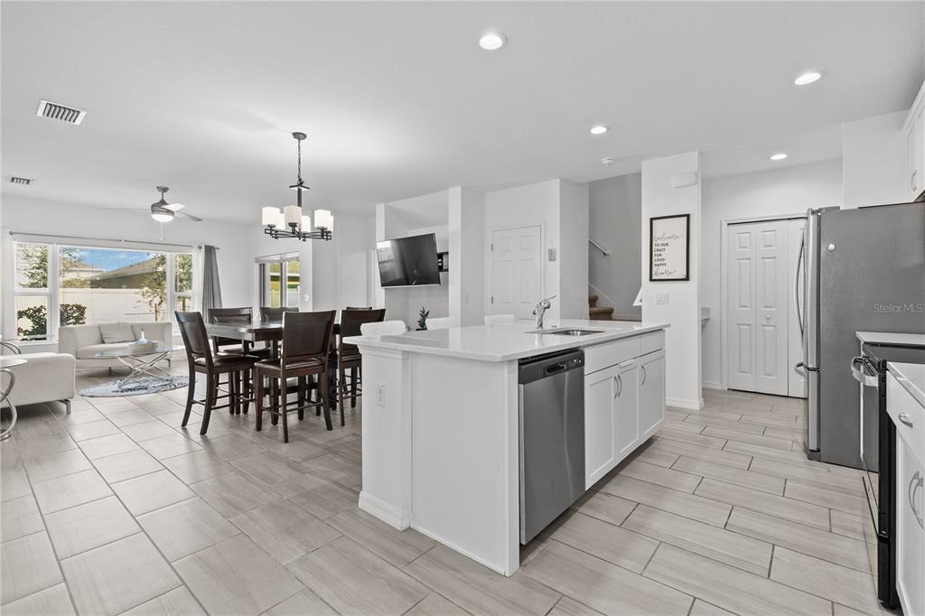A bright, open-concept kitchen and dining area featuring white cabinetry, a large island, and tile flooring — 1286 WISPY CYPRESS DRIVE, KISSIMMEE, FL