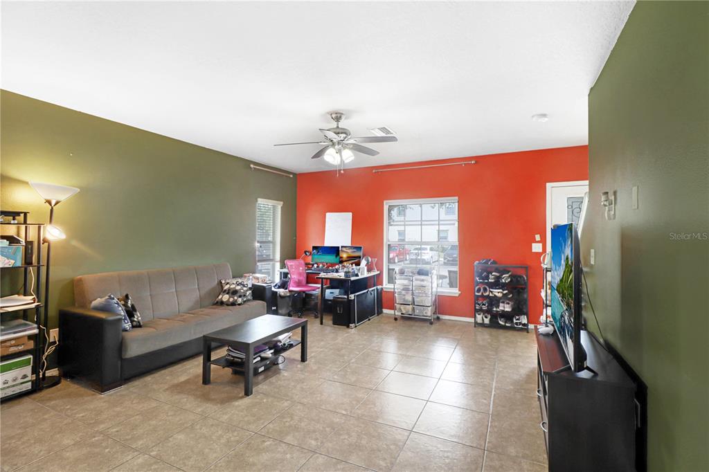 A living room features tile flooring, an olive green wall, an orange accent wall, and furniture — 4605 SOMERSET HILL LANE, RIVERVIEW, FL
