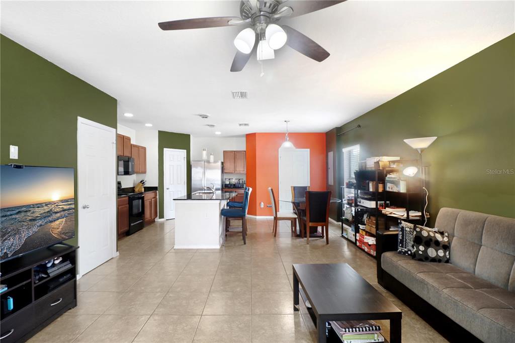 An open-concept living room and kitchen with tile floors, olive green walls, and an orange accent — 4605 SOMERSET HILL LANE, RIVERVIEW, FL