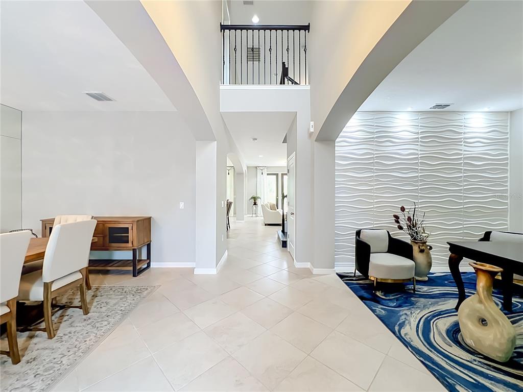 A foyer with tile flooring leads to a living area featuring a textured accent wall — 8316 LOOKOUT POINTE DRIVE, WINDERMERE, FL