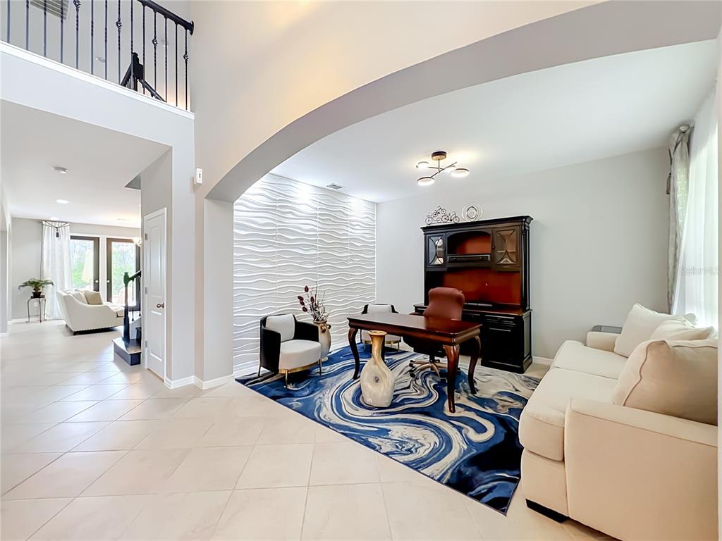 A home office features a textured white wall, a blue patterned rug, and dark furniture — 8316 LOOKOUT POINTE DRIVE, WINDERMERE, FL