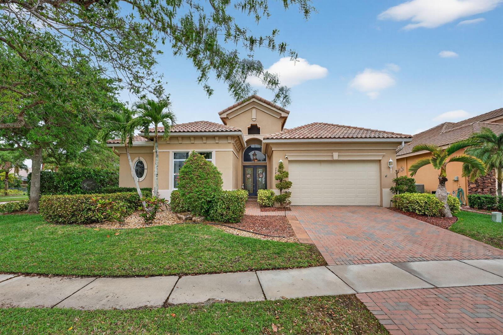 A single-story stucco house with a tile roof and a brick paver driveway — 7741 NW 120th Drive, Parkland FL 33076, PARKLAND, FL