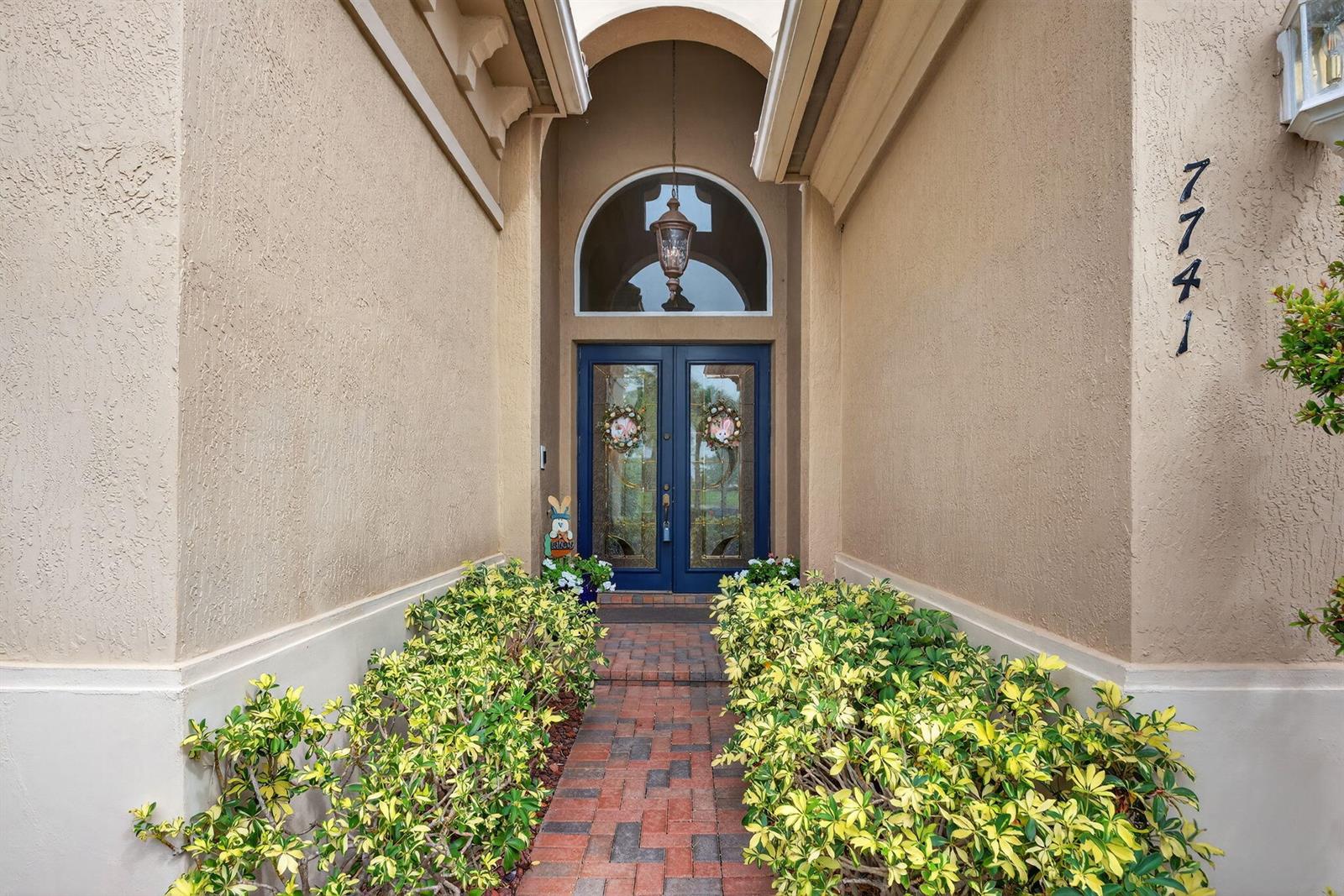 A brick walkway leads to a blue double front door with a decorative arched window — 7741 NW 120th Drive, Parkland FL 33076, PARKLAND, FL