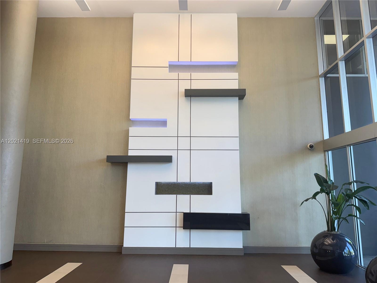 A modern lobby features a large white geometric wall panel with floating shelves and lighting — 290 NW 165th St # 800, Miami FL 33169, MIAMI, FL