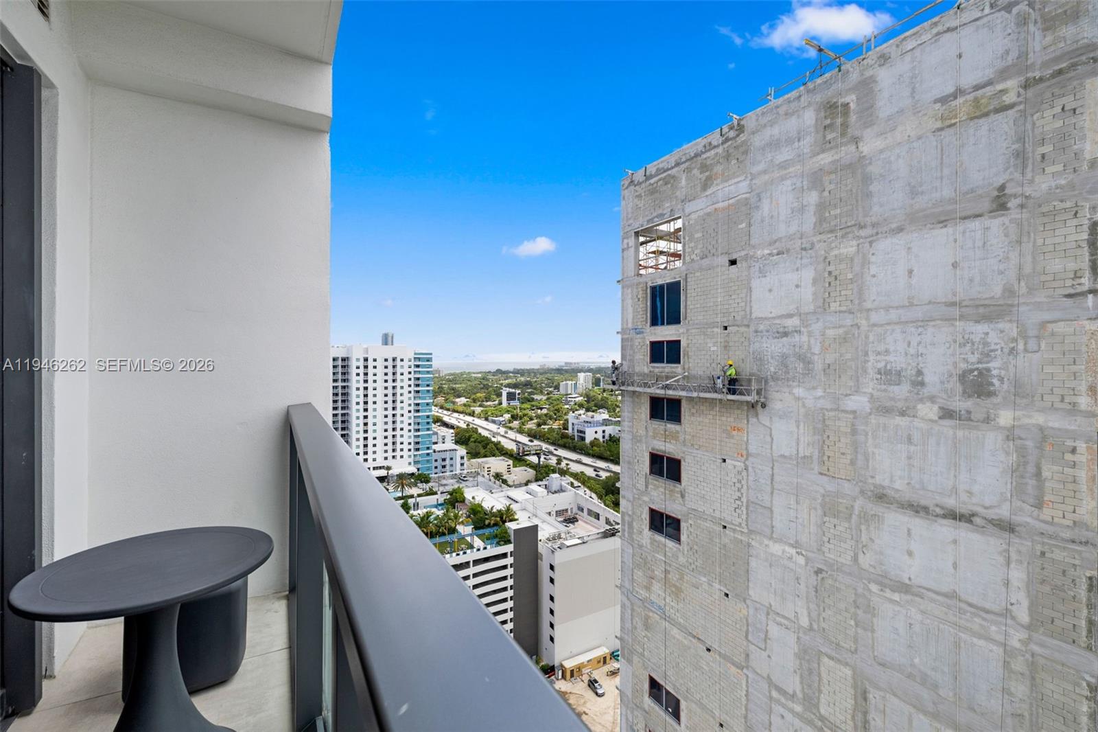 A balcony view shows a small table and a nearby building under construction — 239 SW 9th St # 2303, Miami FL 33130, MIAMI, FL