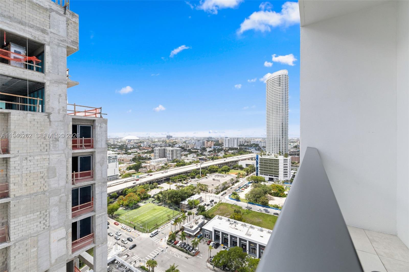 A high-angle view from a balcony overlooks a city street, a highway, and nearby skyscrapers — 239 SW 9th St # 2303, Miami FL 33130, MIAMI, FL