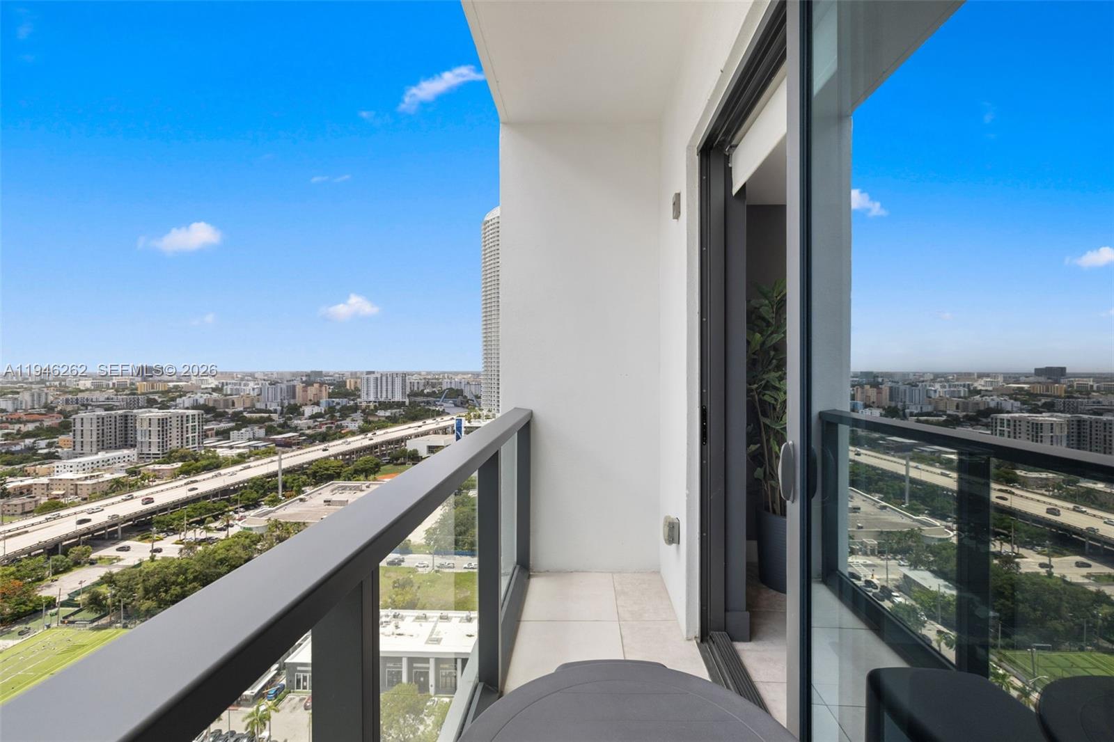 A high-rise balcony features a glass railing overlooking a highway and city skyline — 239 SW 9th St # 2303, Miami FL 33130, MIAMI, FL