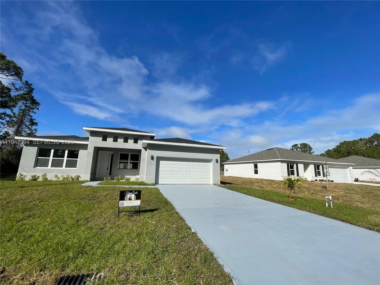 A modern gray single-story house with a two-car garage and a paved driveway — 1326 SEQUOIA RD, Palm Bay FL 32907, PALM BAY, FL
