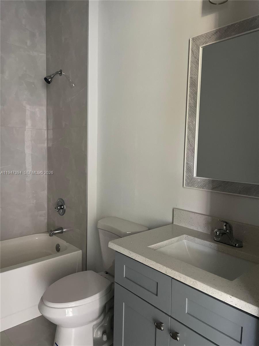 A bathroom features a gray vanity with a stone countertop, a toilet, and a tub — 1326 SEQUOIA RD, Palm Bay FL 32907, PALM BAY, FL