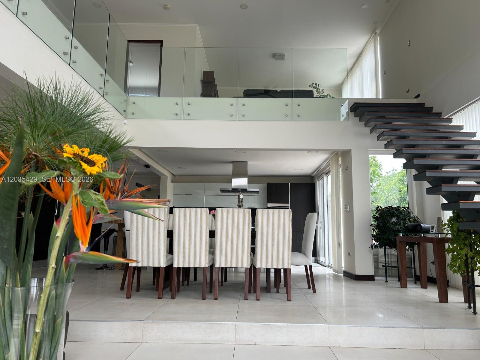 A dining area with striped chairs sits below a mezzanine level with a glass railing — Parcela 12 A Los Molles, OC, OC