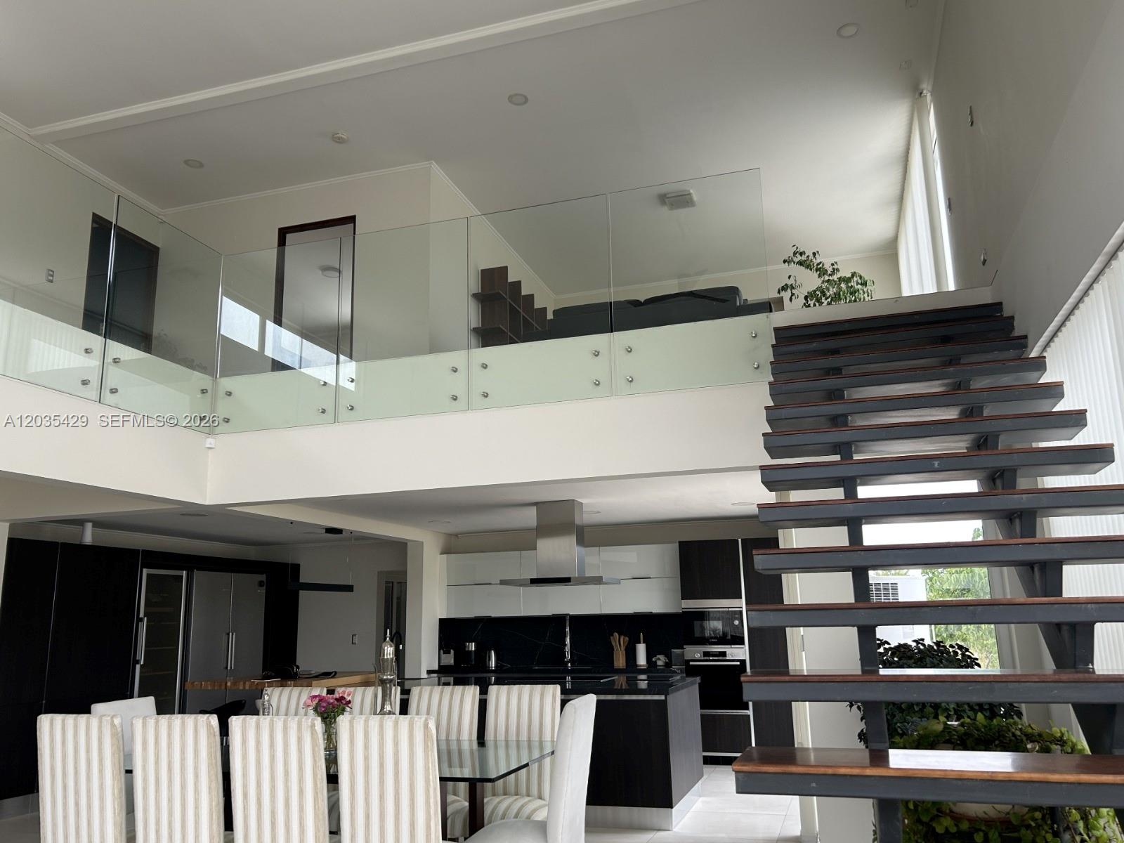 A modern open-plan interior features a dining area, kitchen, and a staircase leading to a loft — Parcela 12 A Los Molles, OC, OC