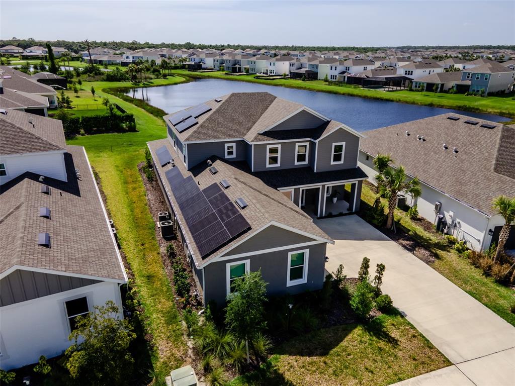 An aerial view of a two-story house with solar panels on the roof near water — 9121 RADIANT CIRCLE, SARASOTA, FL