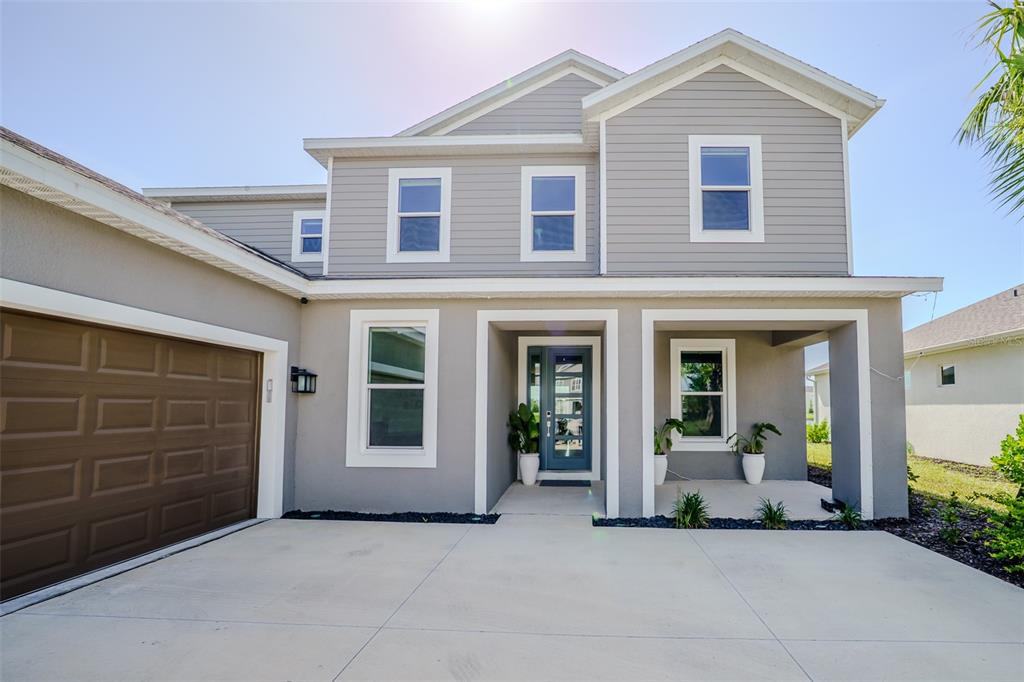 A two-story house with gray siding, a brown garage door, and a covered front porch — 9121 RADIANT CIRCLE, SARASOTA, FL