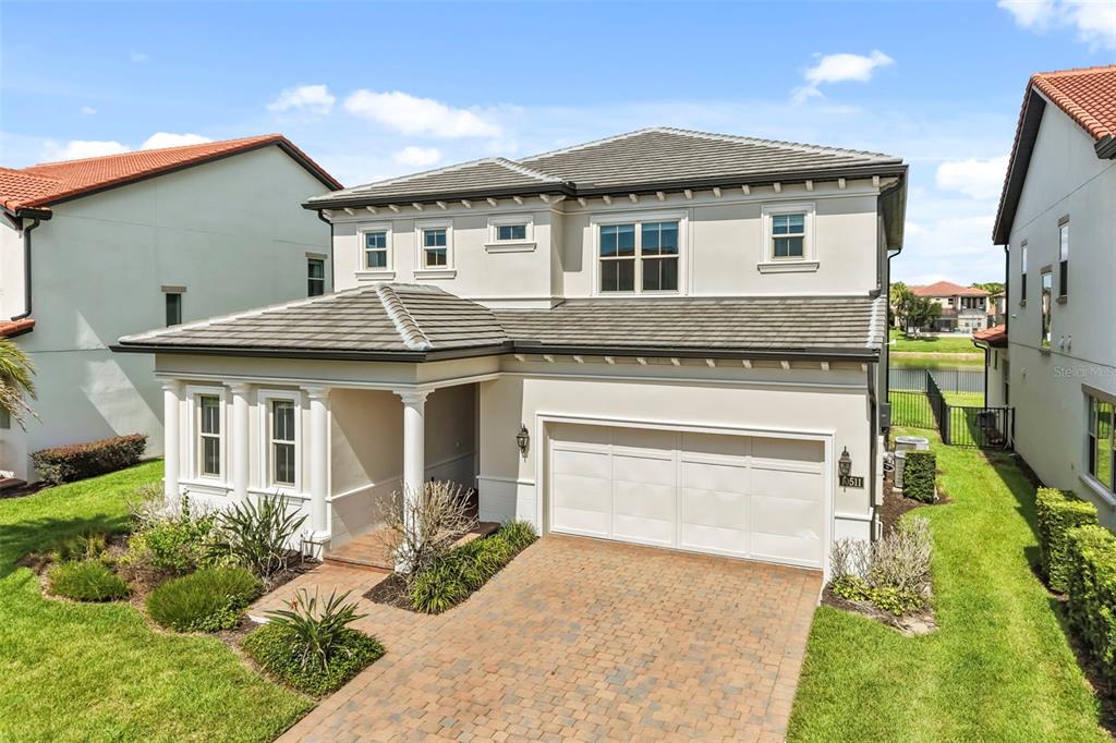A two-story house with a beige stucco exterior, a tiled roof, and a paved driveway — 10511 ROYAL CYPRESS WAY, ORLANDO, FL