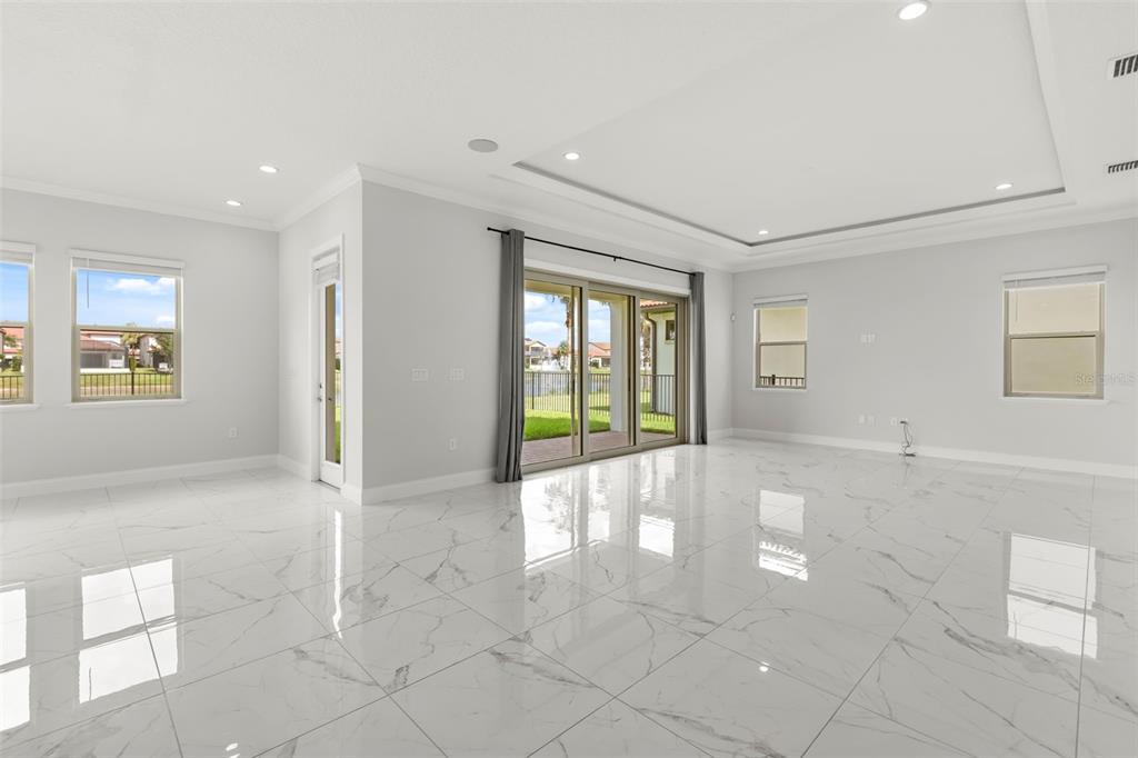 A bright, open-concept living area features white marble-look tile flooring and large sliding glass doors — 10511 ROYAL CYPRESS WAY, ORLANDO, FL