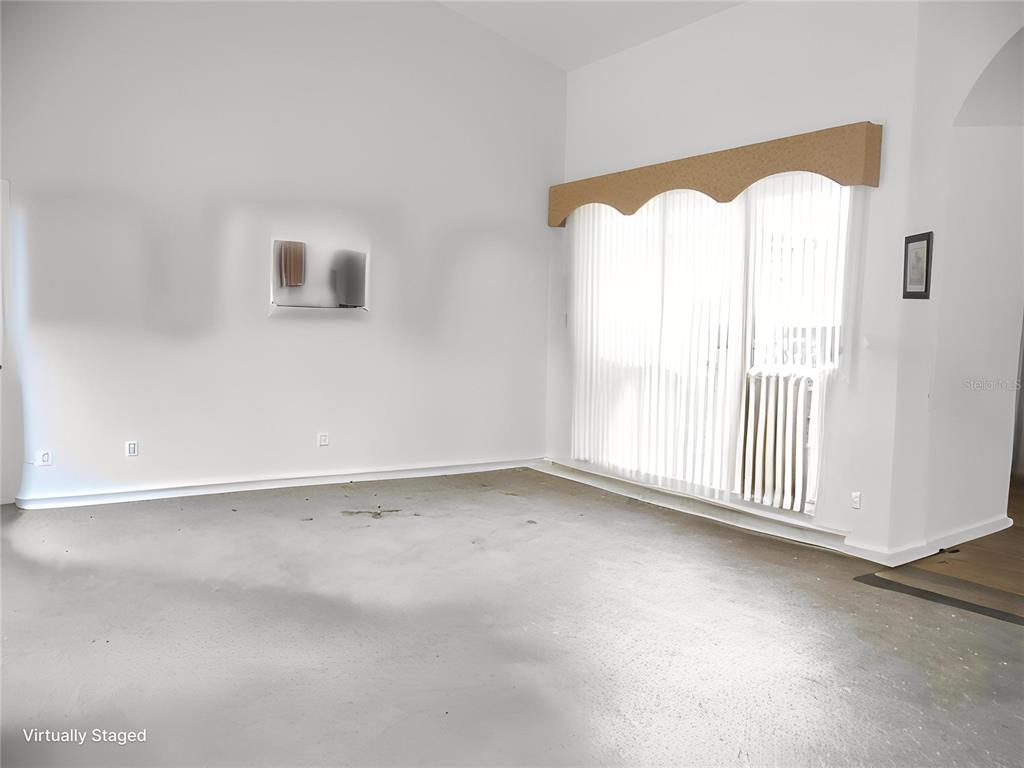 An empty room with white walls, a concrete floor, and a large sliding glass door — 4841 GLEN COE STREET, LEESBURG, FL